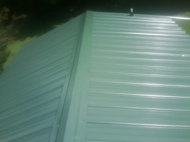 New green metal panels meeting at the ridge of a roof — Flat Roof Repair work by our crew in Canterbury