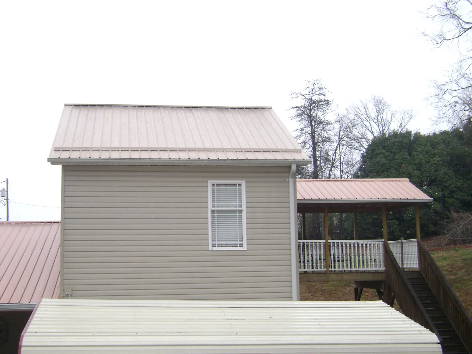 Tan metal roofs on a two story addition and attached porch, from a Roof Replacement job in Canterbury